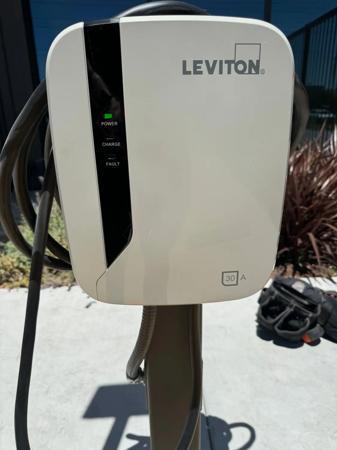 A Level 2 EV charger installed on a pedestal outside a Bakersfield home, its charge cable holstered.