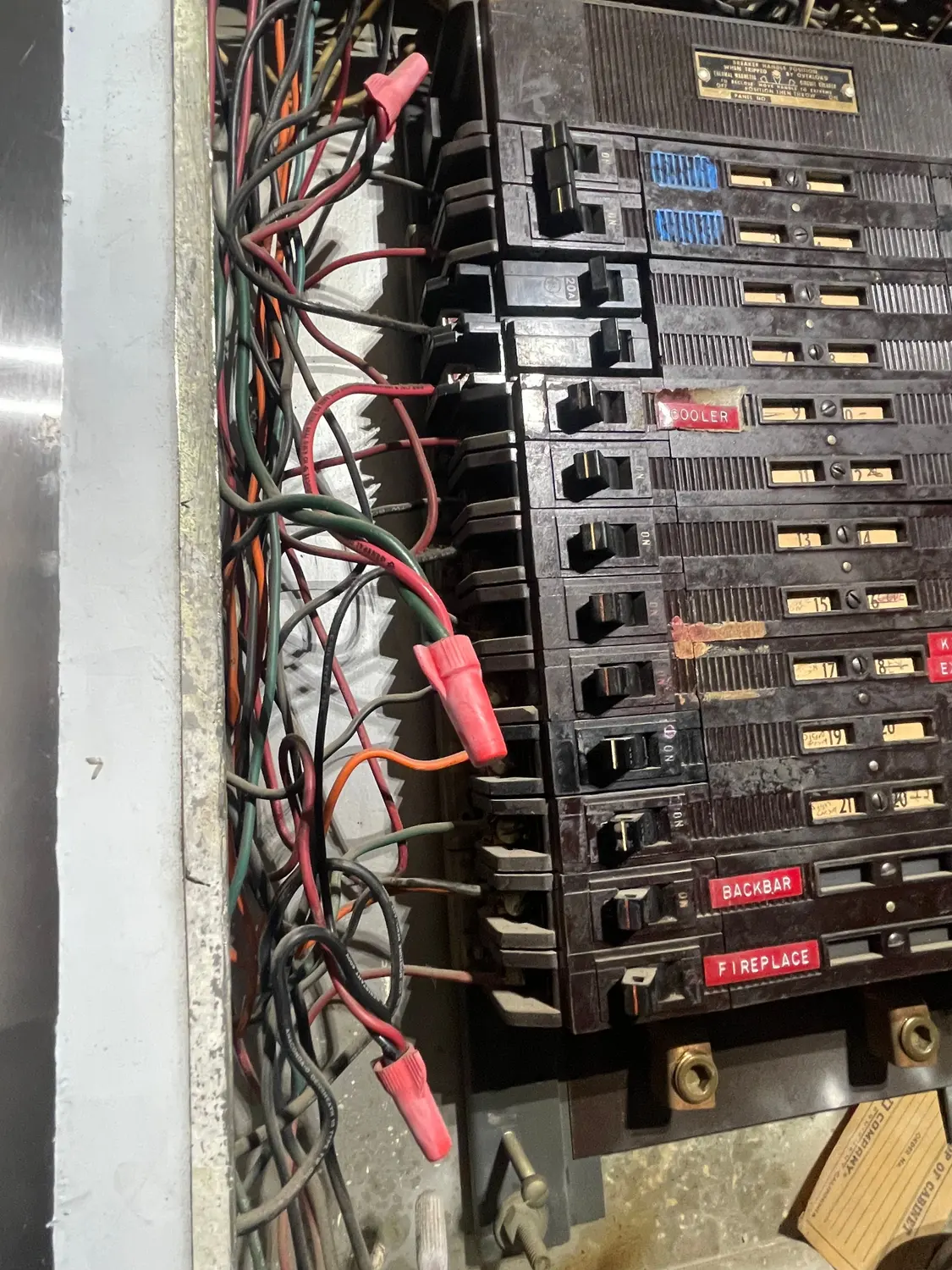 A crowded original electrical panel with every breaker slot filled and hand-lettered labels, before replacement.
